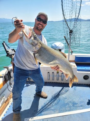 man on boat holding caught fish