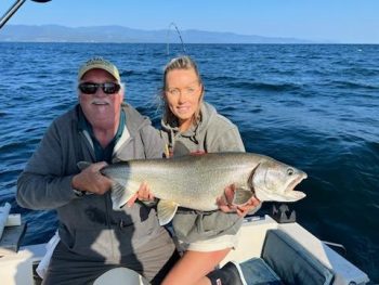 man and woman on boat holding caught fish