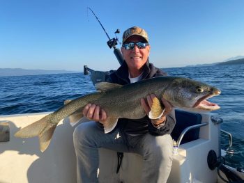 man on boat holding caught fish