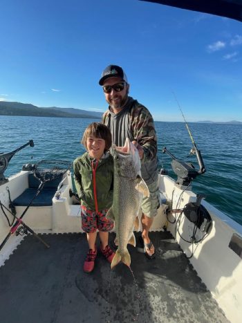 man and son on boat holding caught fish