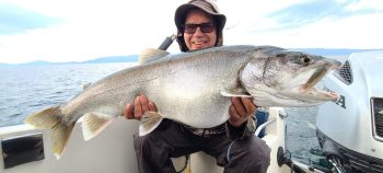man on boat holding caught fish