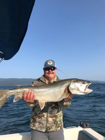 man on boat holding caught fish